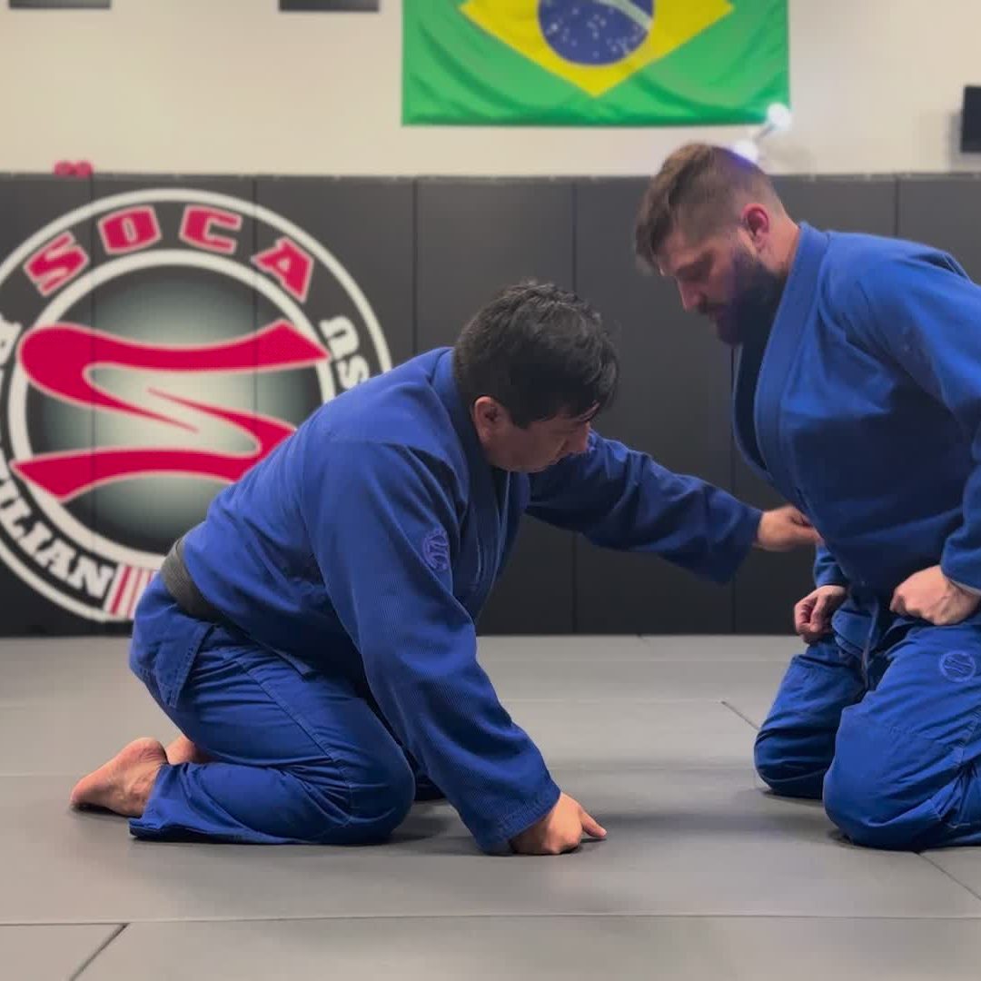 Adults training in the gi beneath the Soca banner and flags